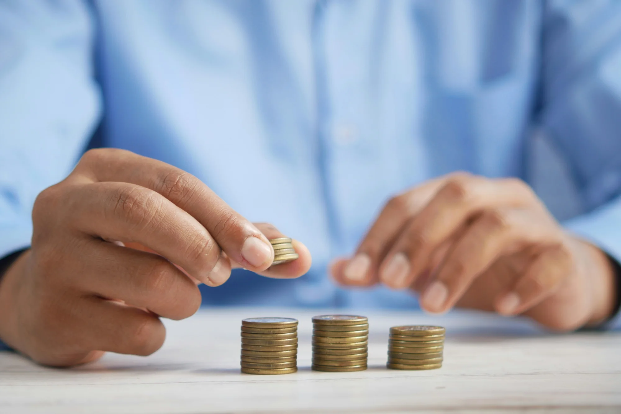 Hands stacking coins to represent incremental business investments and hidden AI costs