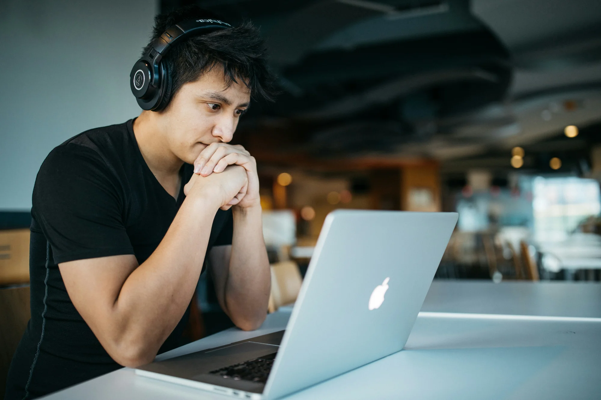 Professional wearing headphones working on a laptop while leveraging AI productivity tools