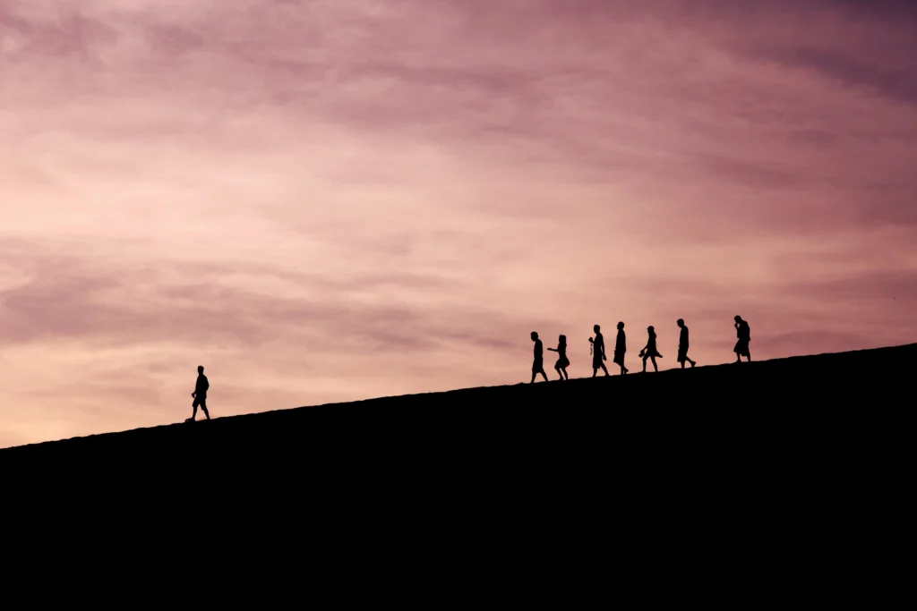 C-suite leadership team walking together up a slope at sunset representing the shared journey of AI-driven organizational transformation.