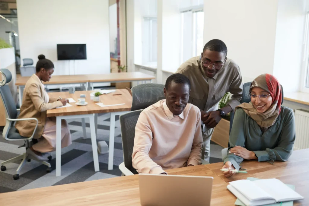 Modern workplace team collaborating over a laptop highlighting collective innovation and overcoming resistance during technology integration.